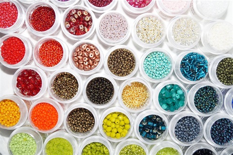 an image of clear circular containers on a white background, each container has its own color of beads with sizes varying slightly between each one