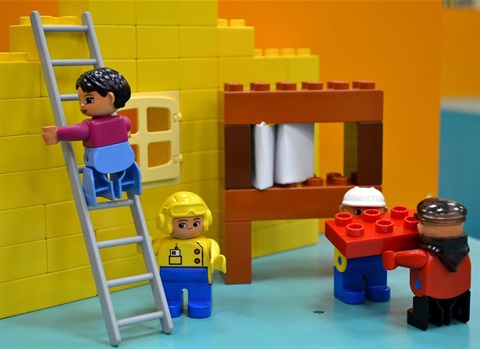 an image of duplo characters posed to look like they are building a house out of duplo bricks